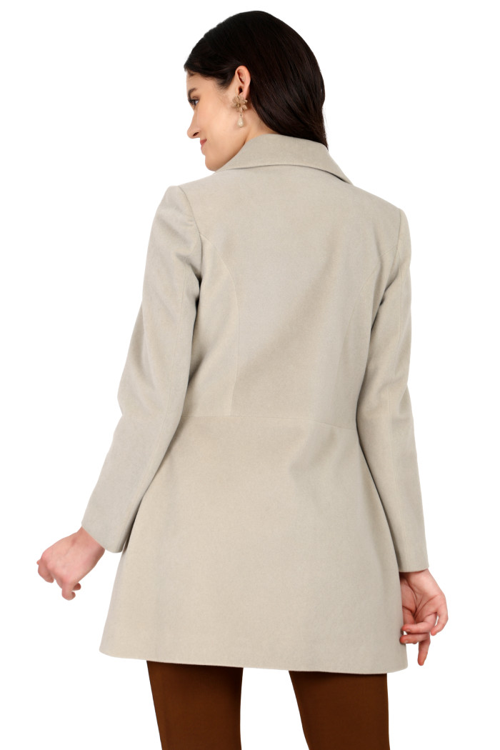 A back pose of a standing woman wearing Trufit’s double-breasted velvet coat in mint green and brown tights.